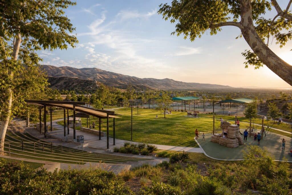Sprawling community park with amphitheater, playgrounds, and sports courts nestled in San Fernando Valley foothills with mountain views.