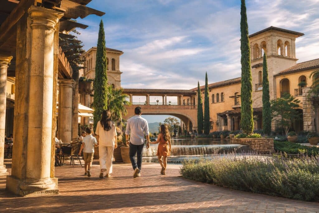 Family enjoying Mediterranean courtyard with fountains and shops in Porter Ranch's Villagio neighborhood during golden hour afternoon.